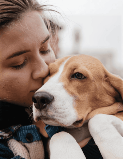 Close-up of woman cuddling her adorable puppy, emphasizing pet love and grooming expertise.