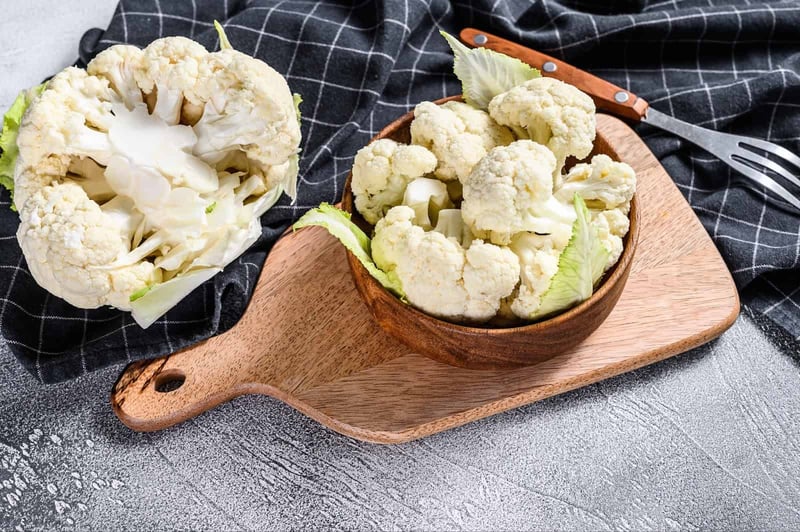 Fresh cauliflower on a wooden board for healthy dog food recipes.