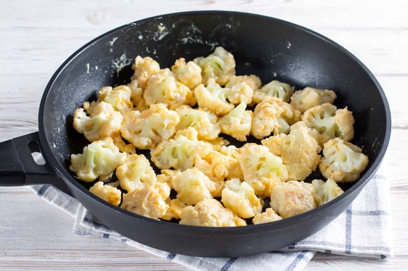 Delicious cauliflower and chicken dog food cooked in a black skillet. Nutritious homemade meal for pets.