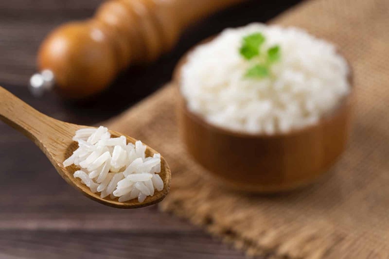 Dogs-friendly cooked rice in a wooden bowl on rustic surface. Perfect for dog diets and serving tips.