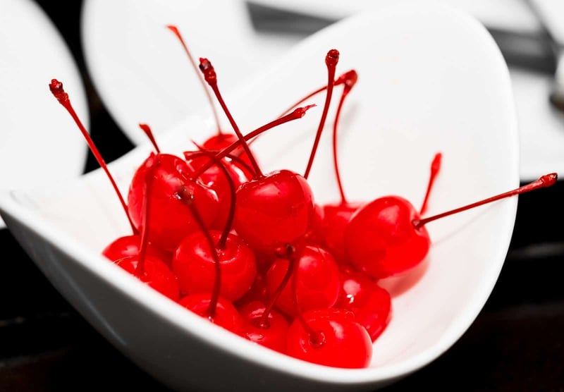 Fresh red cherries in a white bowl, vibrant and ripe for snacking.