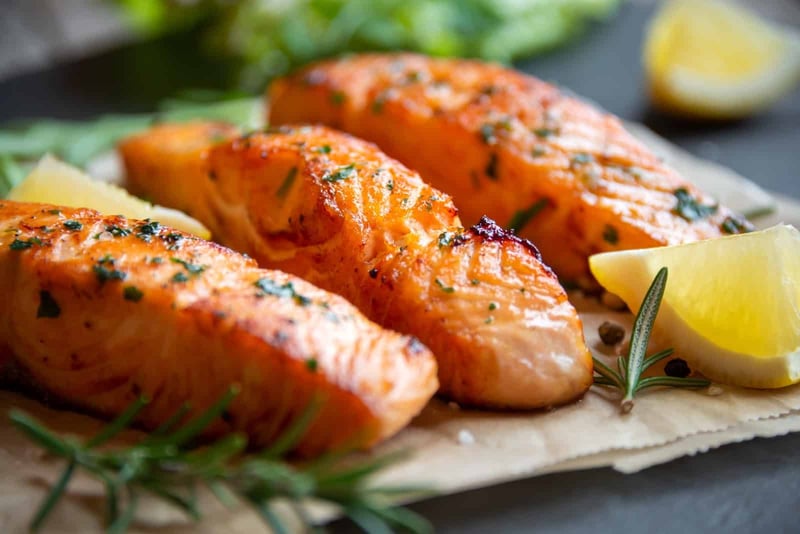 Delicious grilled salmon seasoned with herbs, served with lemon wedges for a fresh, healthy meal. Perfect for dog-friendly diets.