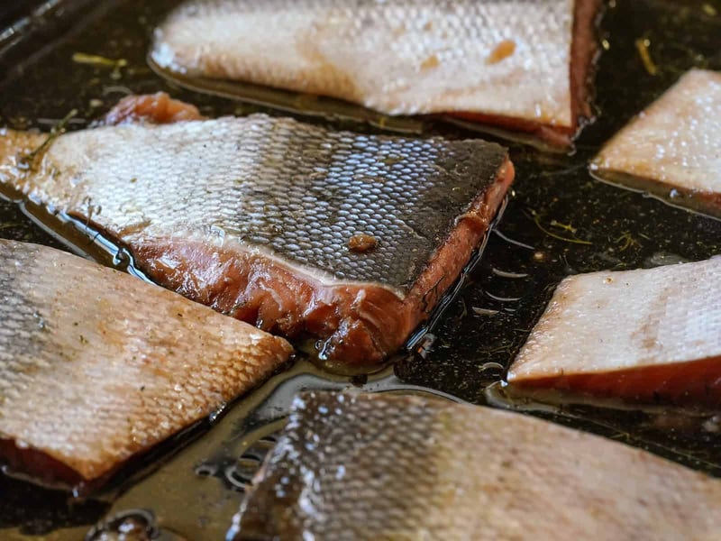 Close-up of fish fillets cooking in oil, highlighting crispy skin and tender flesh, ideal for healthy seafood recipes.