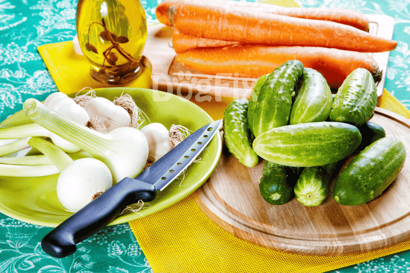Fresh organic vegetables: carrots, cucumbers, garlic, and herbs for dog nutrition.