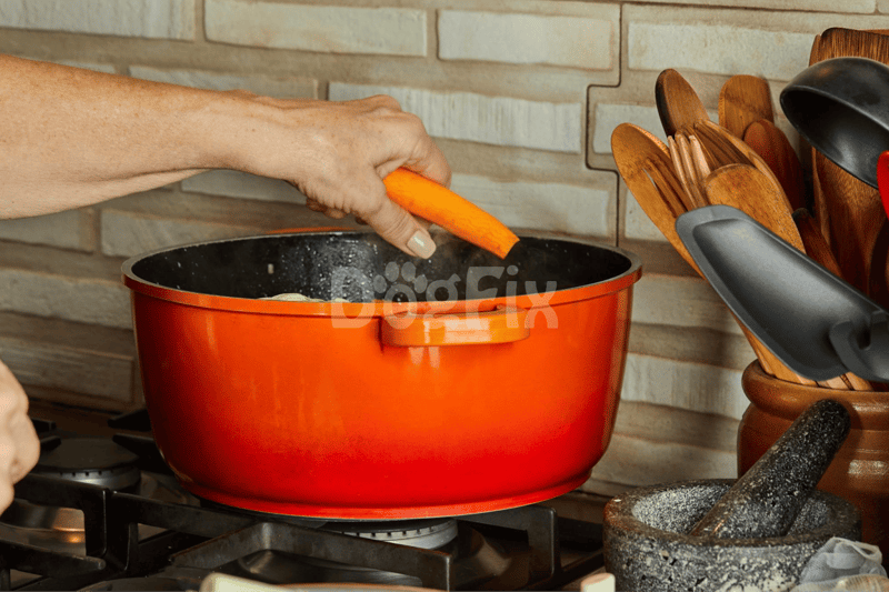 Close-up of a person adding a carrot to a cooking pot in a kitchen scene.
