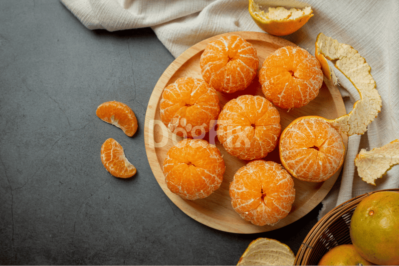 Juicy mandarin oranges with peels on a rustic grey background for healthy eating.
