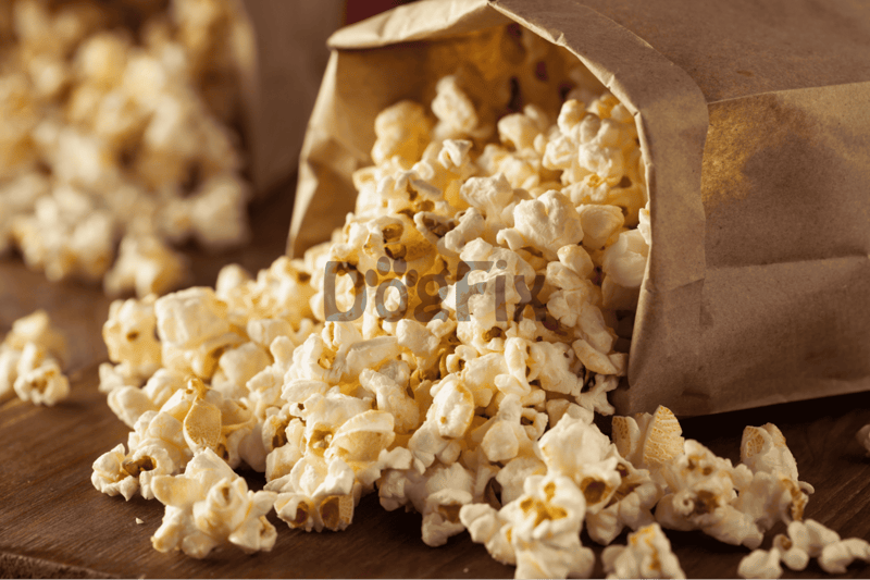 Golden popcorn spilling from a paper bag on a rustic wooden table, ideal for healthy dog treats and snacks from Dogfix.com.