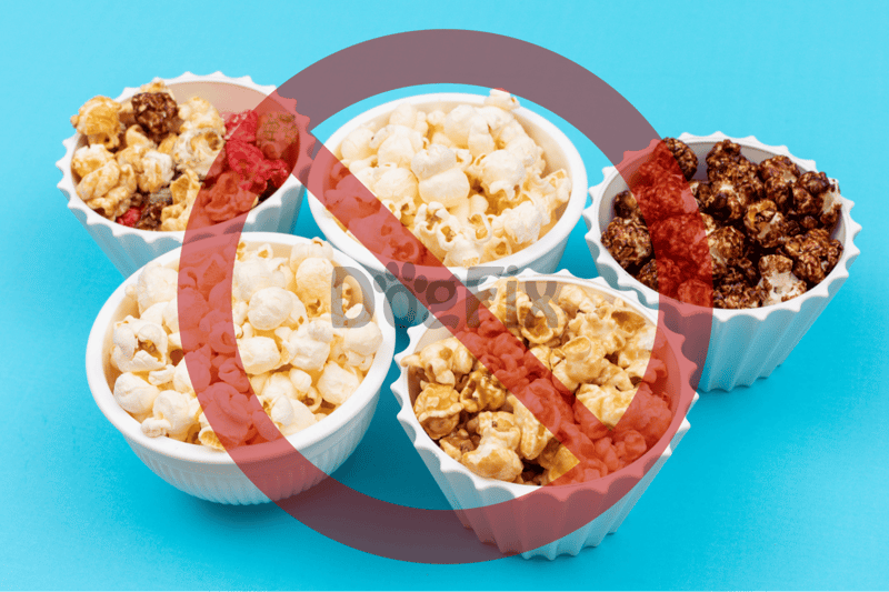 Delicious assortment of popcorn and snack treats in colorful bowls on blue background.