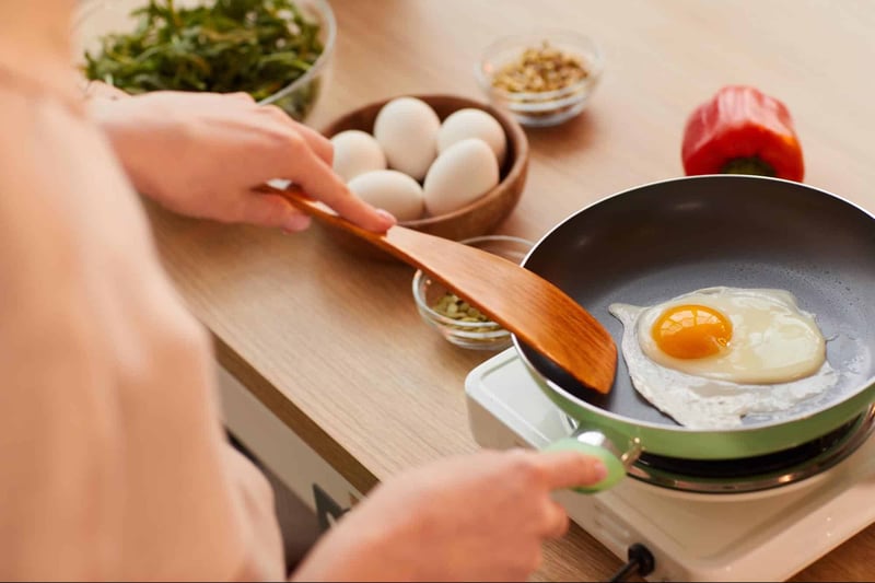 Eggs cooking in frying pan with fresh ingredients around, healthy breakfast idea.