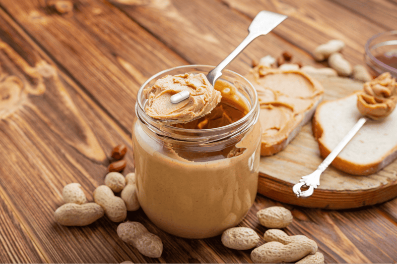 Peanut butter with a pill on a spoon, natural, healthy treat for dogs, on a wooden table.