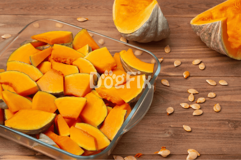 Fresh pumpkin pieces in glass dish with pumpkin seeds on wooden background.