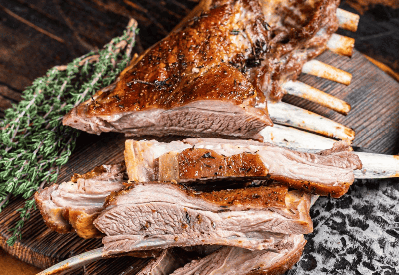 Delicious roasted lamb on a wooden board with herbs, perfect for dog and pet nutrition.