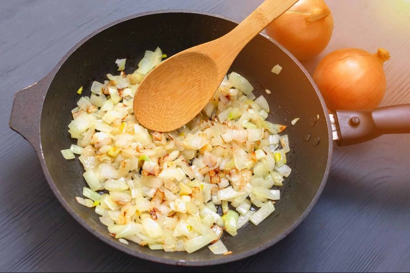 High-quality image of sautéed onions and garlic in a pan for nutritious dog food cooking.