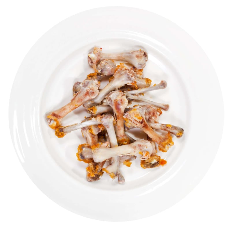 Dog-friendly cooked chicken bones on a white plate.