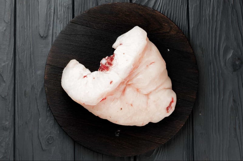 Raw pig fatback on a dark wooden platter for pet diet.