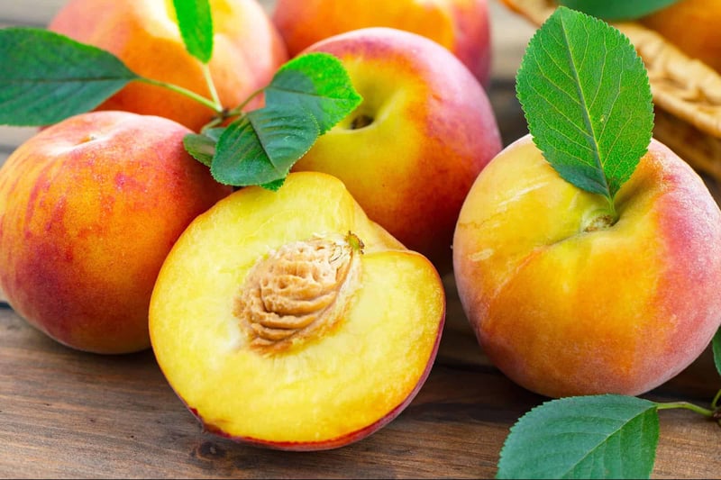 Fresh peaches with vibrant colors and green leaves, perfect for healthy snacks or desserts.