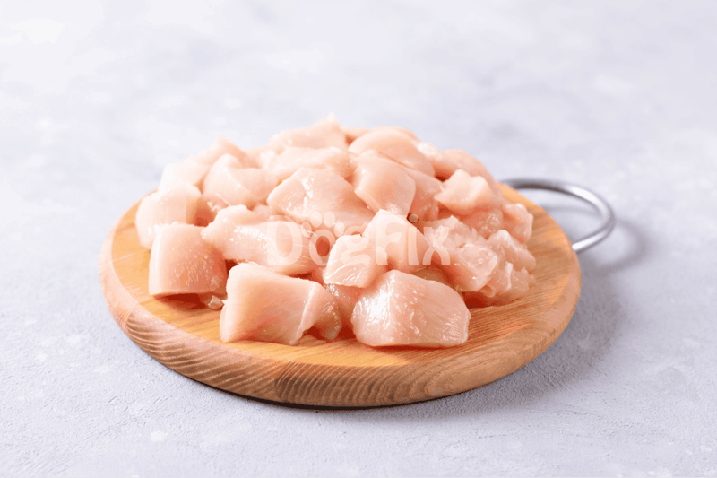 Raw chicken cut into pieces on a wooden board, ideal for homemade dog food.