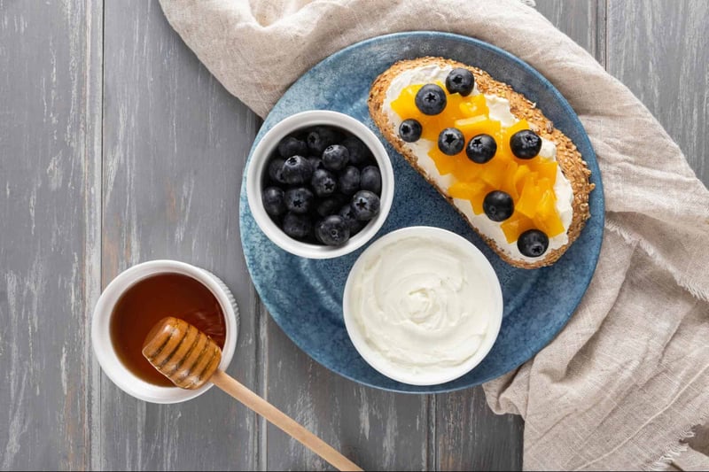Healthy breakfast with berries, yogurt, honey, and bread on a rustic wooden table.