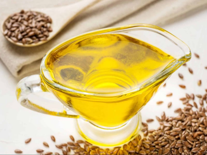 Image of fresh flaxseed oil in a glass pitcher with flaxseeds nearby, used as a nutritional supplement for dogs.