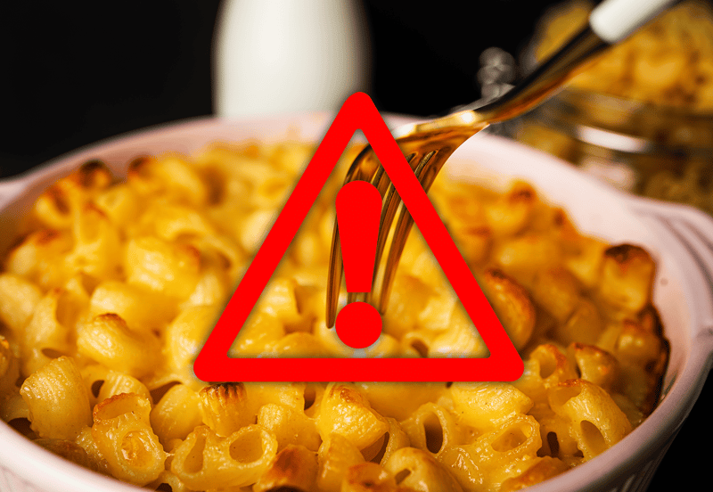 Warning alert over cheesy pasta dish with sauce spilling, highlighting potential allergy risks.