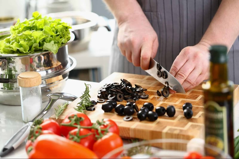 Healthy vegetables being chopped for homemade dog food on a kitchen countertop.