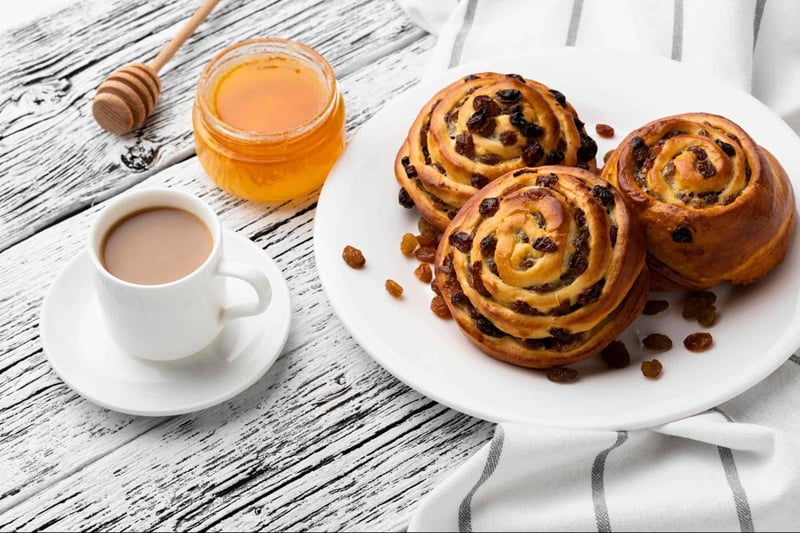 Delicious cinnamon rolls with raisins, honey, and coffee, perfect for breakfast or brunch.