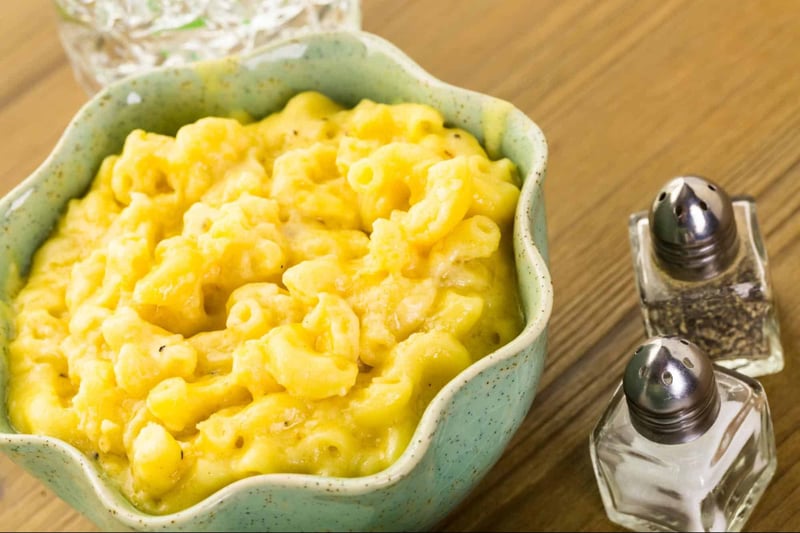 Delicious cheesy macaroni dish in a rustic green bowl on a wooden table.
