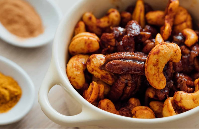 Delicious spiced roasted nuts in a white bowl, ideal snack for any occasion.