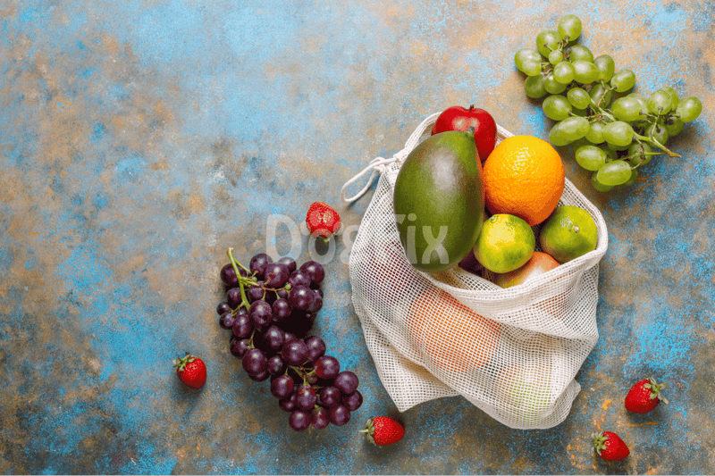 Organic fruits in a reusable bag on a textured surface, healthy snack options.