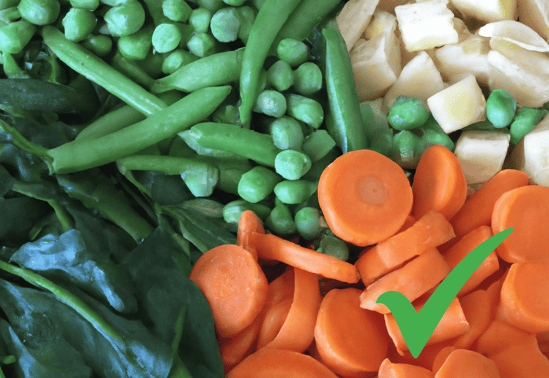 Fresh mixed vegetables including carrots, peas, green beans, and potatoes for canine nutrition.