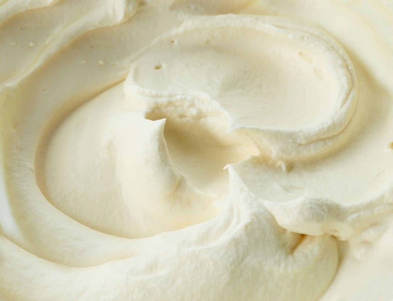 Close-up of creamy cheese spread with smooth texture and swirled appearance.
