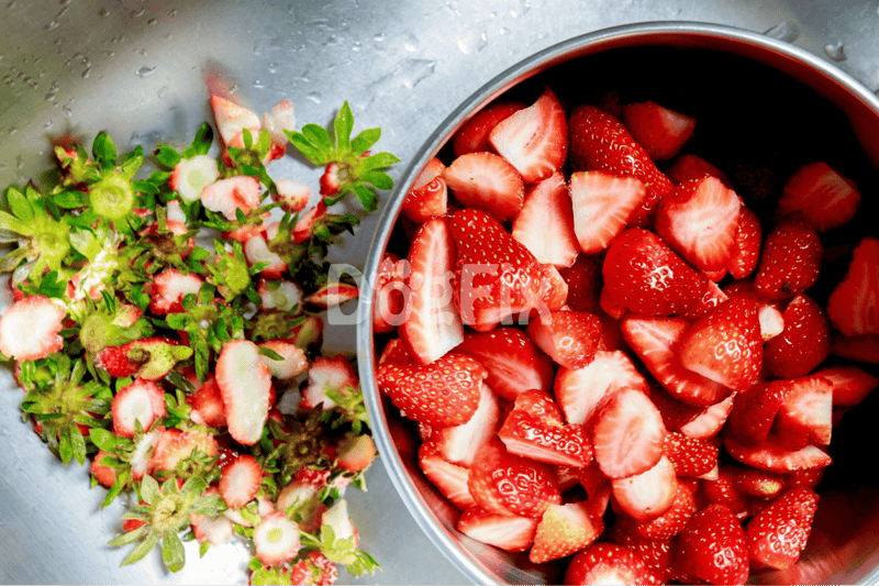 Bright red strawberries chopped and whole, ripe and ready for snacking or dessert preparation.