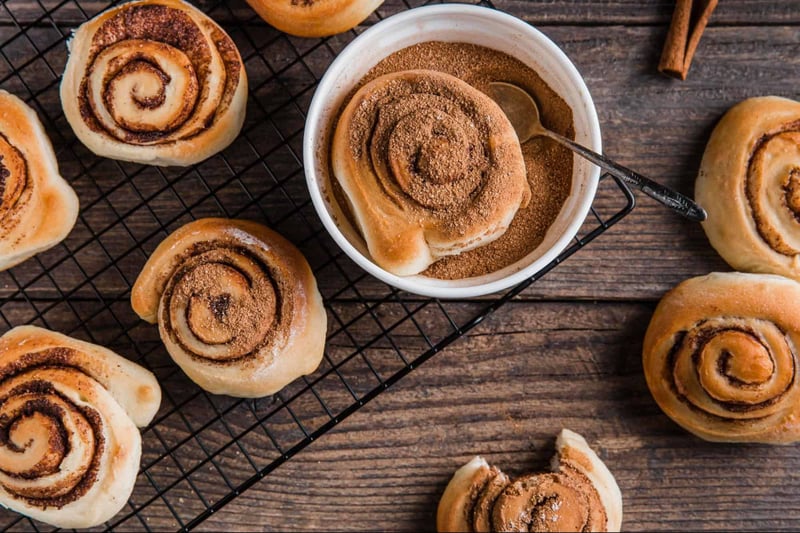 Delicious cinnamon rolls topped with sugar and cinnamon on a rustic wooden table.