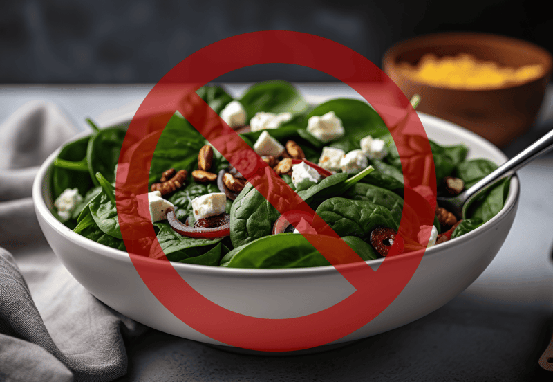 Healthy spinach salad with cheese, nuts, and vegetables, not suitable for dogs.