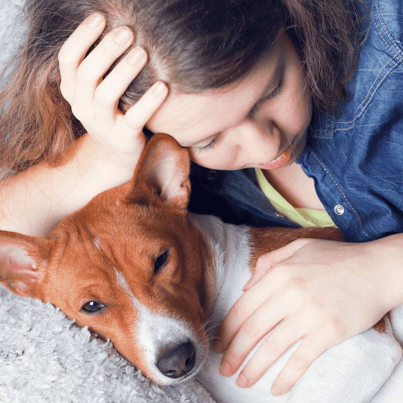 Close-up of woman cuddling her dog, showing affection and companionship.