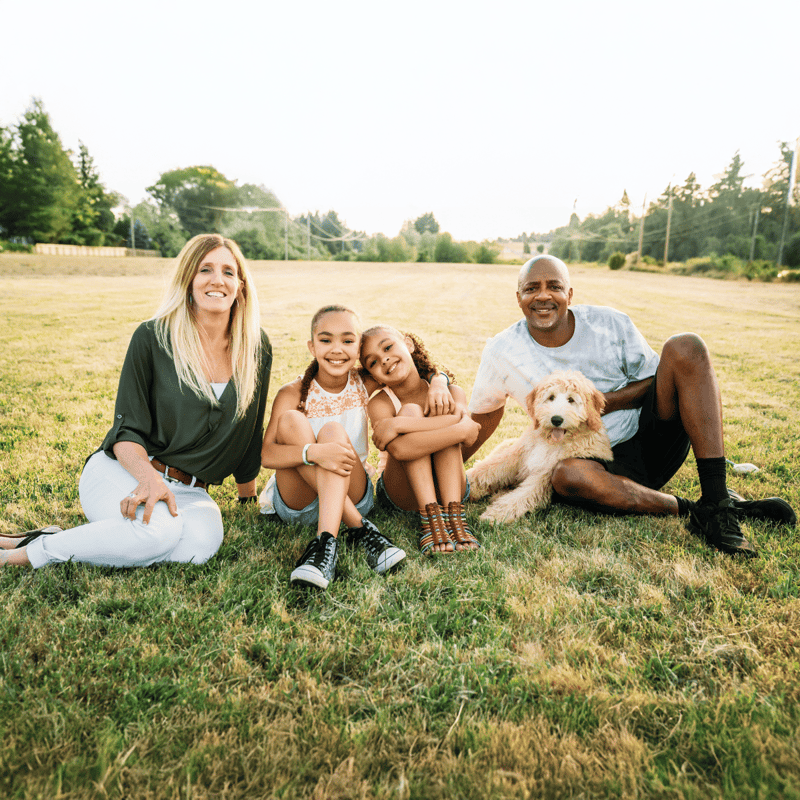 A joyful family enjoying outdoor quality time with their pet dog in a sunny park.