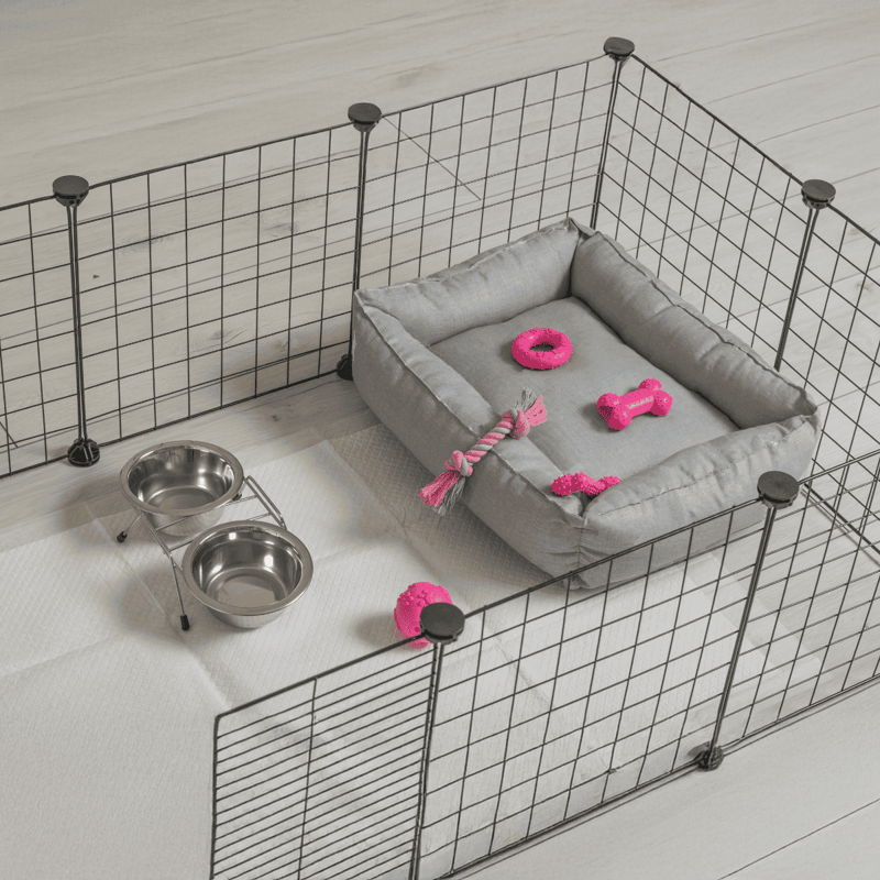 Crate for small dogs with bed, toys, and water bowls inside playpen.