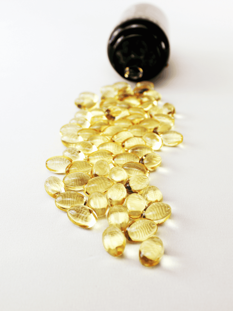 CBD oil spilled from a bottle onto a white surface.