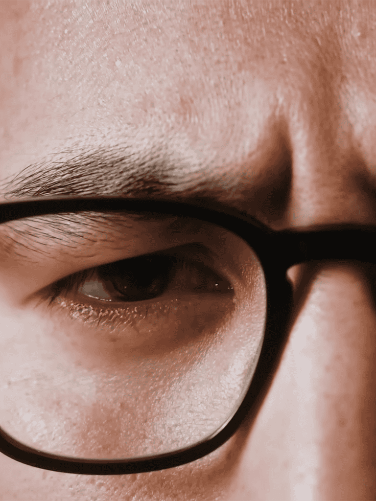 Close-up of a person wearing glasses showing eye detail and skin texture.