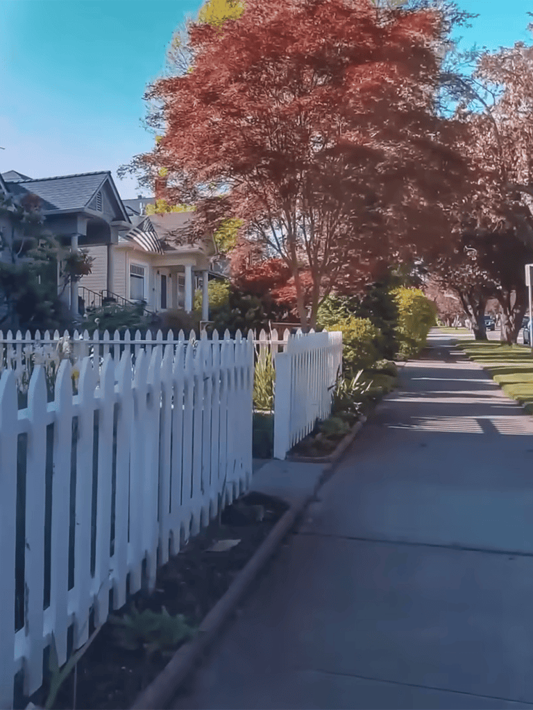 White picket fence with lush landscape.