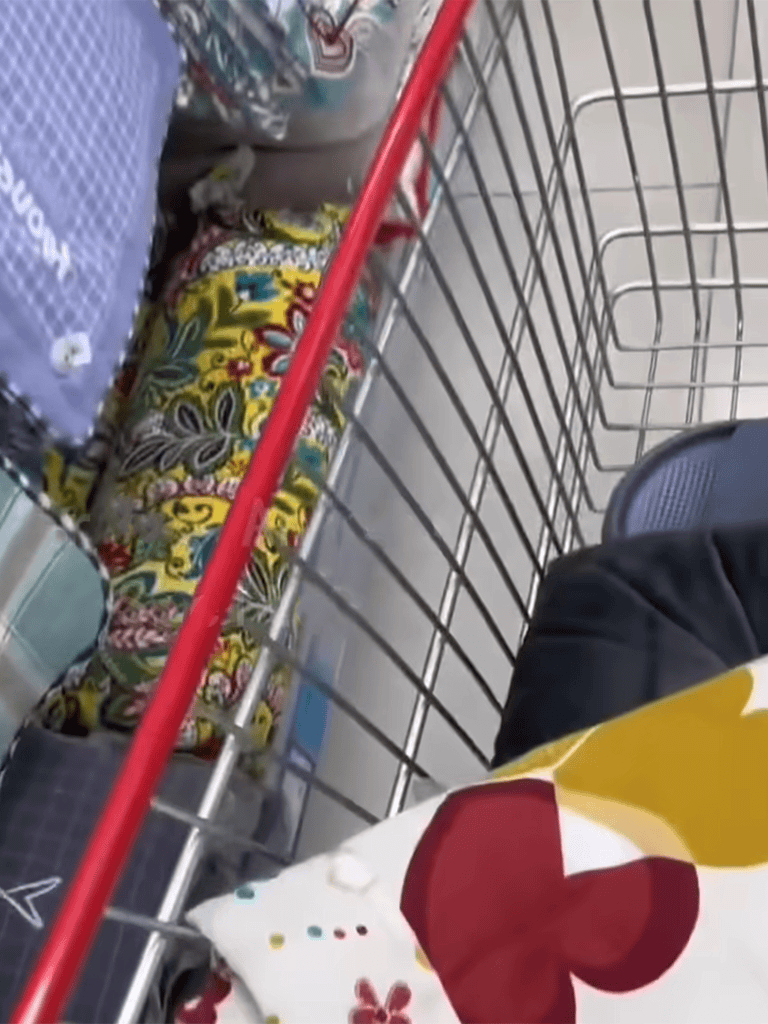 Unorganized supermarket shopping cart filled with groceries, bags, and food items.