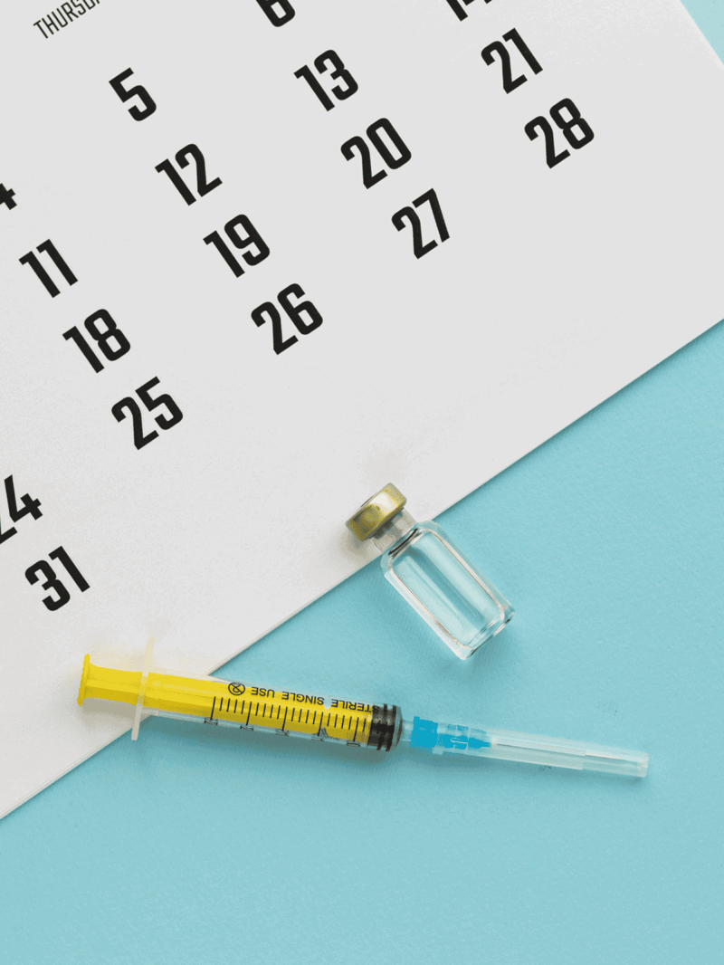 Properly labeled calendar, syringe, and vaccine vial for pet health and vaccinations.