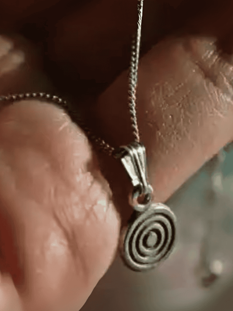 Jewelry pendant with spiral design on silver chain, stylish accessory suitable for men and women.