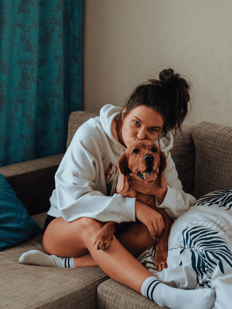 Adorable woman cuddling her playful golden retriever at home.