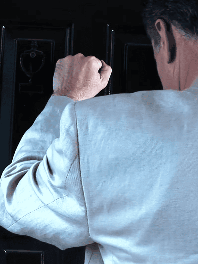 Alt: Locksmith unlocking a black door with a tool, professional security service.