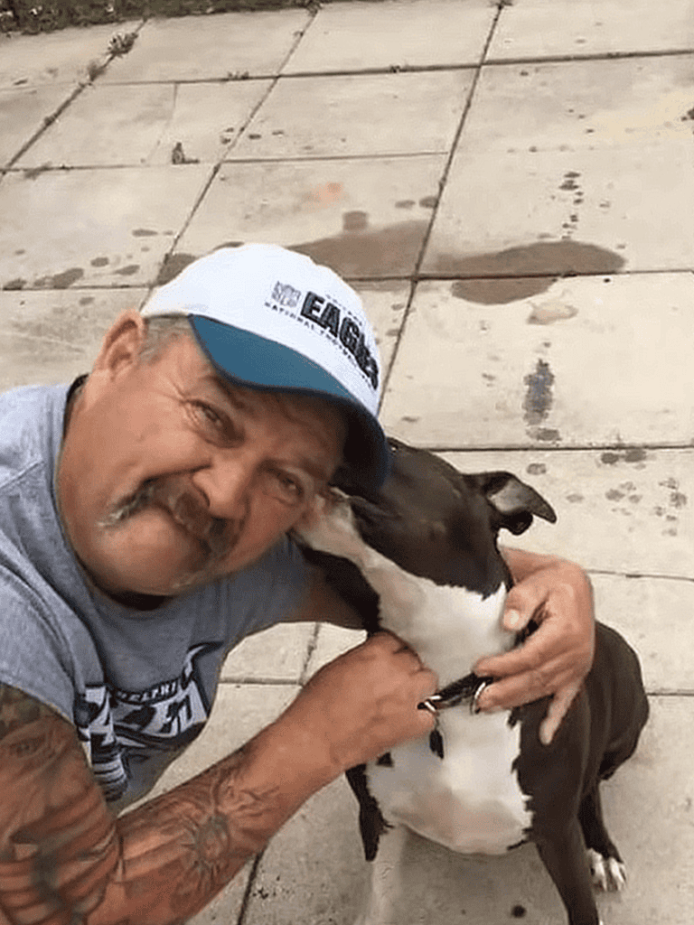 Man hugging his playful dog outdoors, bonding and enjoying time together.