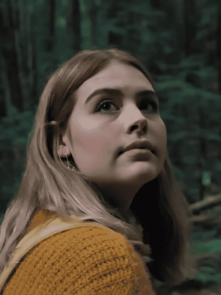 Woman in forest with lush greenery, natural setting, contemplative expression, outdoor scenery.