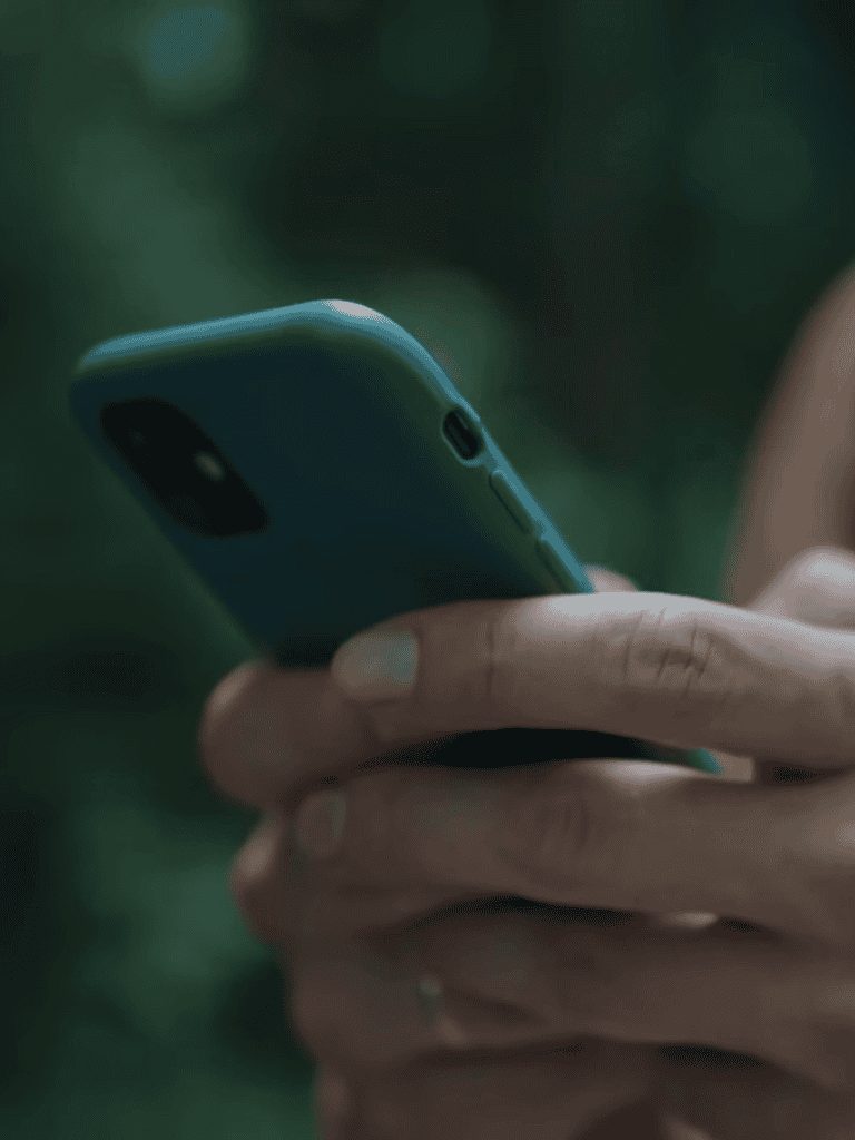 Close-up of a person using a smartphone outdoors.