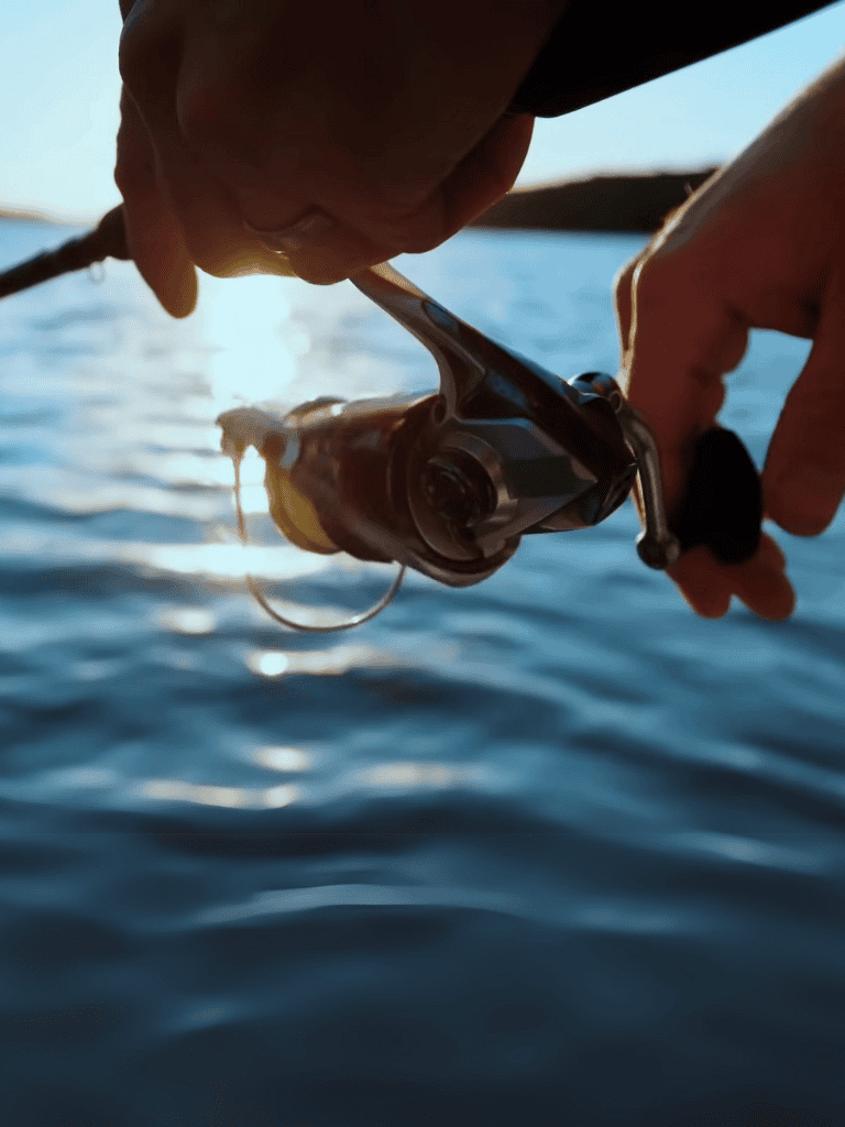 Close-up of a person reeling in a fish on a boat. Perfect for fishing and outdoor adventure enthusiasts.