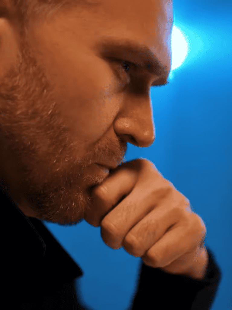Close-up of a man deep in thought, hand resting on chin, reflective mood.